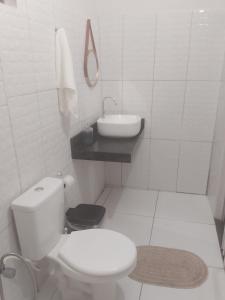a white bathroom with a toilet and a sink at Cantinho da Rosa in Santo Amaro