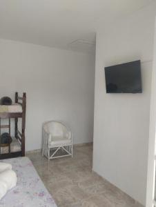 a bedroom with a bed and a tv and a chair at Novo Encanto in Ubatuba