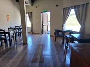 una sala da pranzo con tavoli, sedie e una porta di Hostel Lagos del Sur a El Chalten