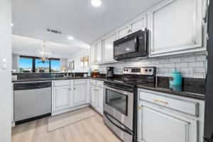 a kitchen with white cabinets and black appliances at Wind Drift North 211-NEW-Bayfront-Beach access-Boat Slips-Sleeps 8 in Orange Beach