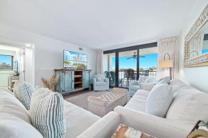 a living room with white couches and a television at Wind Drift North 211-NEW-Bayfront-Beach access-Boat Slips-Sleeps 8 in Orange Beach