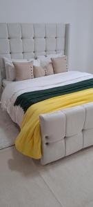 ALPHAROSE SUITES, Nursan Muthaiga Homes في نانيوكي: سرير ابيض وعليه بطانيه صفراء