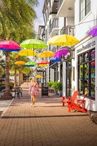 达尼丁Cozy Coastal Cottages of Dunedin 1的带着一把伞沿着街道走的女人