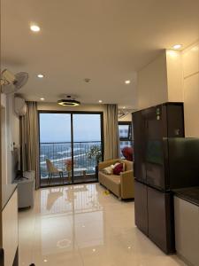 ein Wohnzimmer mit Couch und Kühlschrank in der Unterkunft Penthouse S202 Homestay BBQ Vinhomes Grand Park in Gò Công