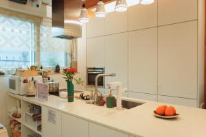 a kitchen with white cabinets and a sink with oranges on a counter at SeoulView Guest House in Seoul +39 photos
