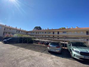 Dos coches estacionados en un estacionamiento frente a un edificio. en Magnifique T2 Cabine - Proche Plage & Commerces - FR-1-816-32, en La Favière