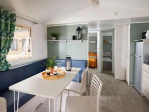 Saint-Martin-de-BremMobil-home 4 pers avec terrasse à Brem - API-1-52-438的厨房和餐厅配有白色桌子和椅子