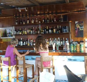 two girls sitting at a bar in a room with alcohol at Fassolou in Faros