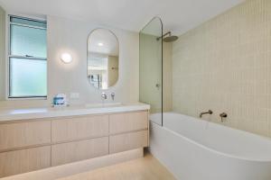 un bagno con vasca, lavandino e specchio di Serenity Apartments Noosa a Noosa Heads