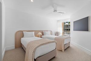 2 letti in una camera con TV a schermo piatto di Serenity Apartments Noosa a Noosa Heads