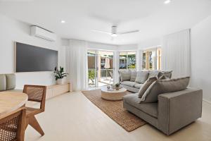 un soggiorno con divano e TV a schermo piatto di Serenity Apartments Noosa a Noosa Heads