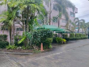 ein Gebäude mit Bäumen und Pflanzen vor einer Straße in der Unterkunft Bann Lhong Rak Krabi in Krabi