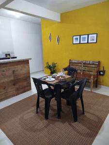 uma sala de jantar com mesa e cadeiras e uma parede amarela em Loft aconchegante Estou em Arraial em Arraial do Cabo