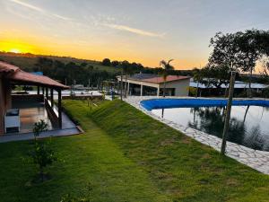 a resort with a swimming pool with a sunset in the background at Chácara mana in Anápolis