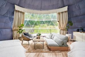 ein Wohnzimmer mit Couch und großem Fenster in der Unterkunft Glampseason in Sendai