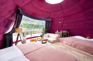 ein Schlafzimmer mit zwei Betten und einer lila Decke in der Unterkunft Glampseason in Sendai + 1 Foto