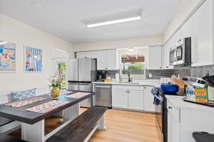 a kitchen with white cabinets and a table with two benches at Your own 5BR Private Oasis! wPrivate PoolPickleball in West Palm Beach