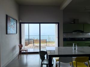 een keuken met een tafel en stoelen en uitzicht op de oceaan bij Windy Cove by bukroom in Pīrmed