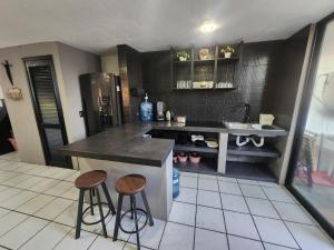 a kitchen with a counter and two stools in it at Casa entera, elegante, moderna in Guadalajara
