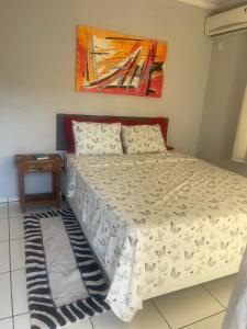 ein Bett in einem Schlafzimmer mit einem Gemälde an der Wand in der Unterkunft Lugar pra relaxar...Perto de tudo .. in Búzios