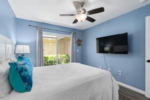 een slaapkamer met een wit bed en een plafondventilator bij Home Away from Home Beach Villa in Honokai Hale