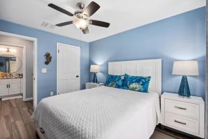 een blauwe slaapkamer met een bed en een plafondventilator bij Home Away from Home Beach Villa in Honokai Hale