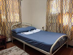 a bed in a room with curtains and a blue mattress at Maru Vibe Guest house at Panicsican San Juan Elyu in San Juan
