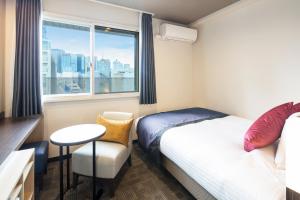 mały pokój z łóżkiem, stołem i oknem w obiekcie HOTEL MYSTAYS Kanda w Tokio