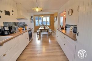 a kitchen with white cabinets and a wooden floor at St christophe in Lézardrieux