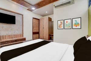 艾哈迈达巴德Super Hotel O Naroda GIDC Formerly Yuvraj的卧室里有一张白色的床和一台平板电视 更多22张照片
