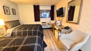 a hotel room with a bed and a desk and a television at Confederation Inn in Saskatoon