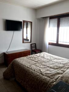 een slaapkamer met een bed en een tv aan de muur bij Casa Amplia Para 6 personas in Necochea