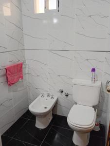 een witte badkamer met een toilet en een wastafel bij Casa Amplia Para 6 personas in Necochea