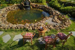 a pond with chairs and a table in a yard at Cheers Ecolodge Du Già in Làng Cac +53 photos