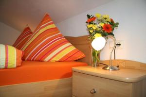 an orange bed with a vase of flowers and a lamp at Landhaus Suntheim in Wertach