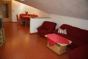 a living room with two red couches and a table at Landhaus Suntheim in Wertach