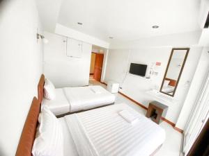 a white room with two beds and a mirror at Baan Rim Khong Hotel in Ban Tha Khwai
