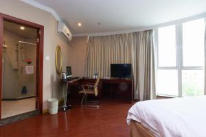 a bedroom with a bed and a desk with a television at GreenTree Inn Shanghai Songjiang Xinqiao Jiuxin Road Express Hotel in Chunshen