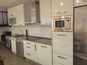 a kitchen with white cabinets and a microwave at Casa Rural El Zumaque in Pereña