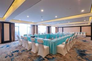 a large banquet hall with a long table and white chairs at Xana Hotelle·Heyuan Hongxing Road in Heyuan