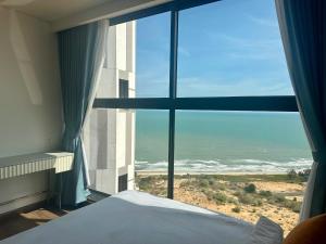 a bedroom with a view of the ocean from a window at Apec Mandala Sea View Bathtub by MLT in Mui Ne