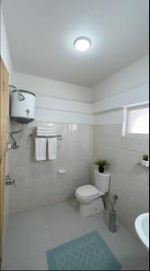 a white bathroom with a toilet and a sink at Hotel BHRIGU in Manāli