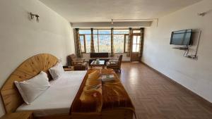 a bedroom with a large bed and a living room at Hotel BHRIGU in Manāli