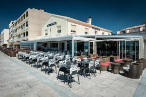 a group of tables and chairs in front of a building at Hôtel Restaurant le Voilis in Le Grau-dʼAgde