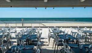 a group of tables and chairs at the beach at Hôtel Restaurant le Voilis in Le Grau-dʼAgde