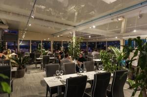 ein Restaurant mit Tischen und Stühlen mit Leuten, die darauf sitzen in der Unterkunft Hôtel Restaurant le Voilis in Le Grau-dʼAgde