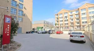 a parking lot with cars parked in front of a building at GreenTree Inn Express Zhangjiagang Hexing Town Shazhou Professional Institue of Technology in Qiwei