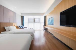 una camera d'albergo con due letti e una TV a schermo piatto di Gya Hotel Chengdu Global Center Jinchenghu Metro Station a Chengdu