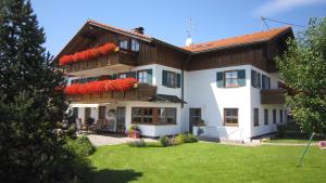 a large white house with red flowers on the balconies at Landhaus Suntheim in Wertach