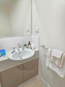 Cairns NorthにあるAllure at The Edge 3brm luxury apartment with coffee machine and 2 pools!の洗面台と鏡のある白いバスルーム